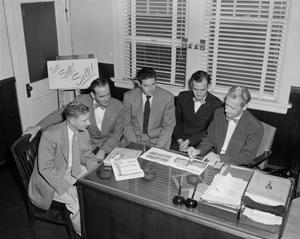 [Photograph of five men in an office]