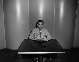 [Photo of man sitting at table]