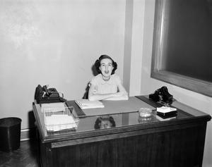 [Photograph of woman at desk]