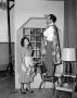 Photograph: [Photo of Melvin Dacus and a woman hanging curtains]