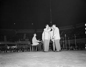[Photograph of four men singing on stage]