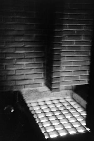 [Photograph of a brick wall and a metal grate]
