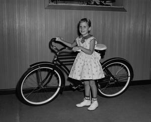 [Photograph of a girl with a bicycle]