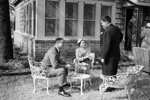 [Photograph of individuals sitting in lawn furniture]