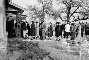 [Photograph of a group of individuals lined up in front of a house]