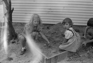 [Photograph of two little girls playing in a sandbox]