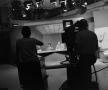 Photograph: [Photograph of camera operators silhouette filming news team]