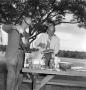 Photograph: [Two men at a picnic table]