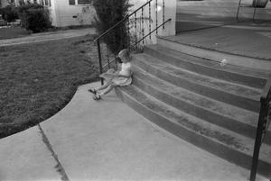 [Photograph of a little girl sitting on porch steps]