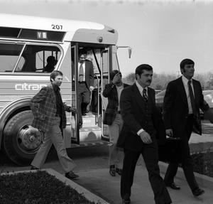 [Photograph of a group of men exiting a bus]