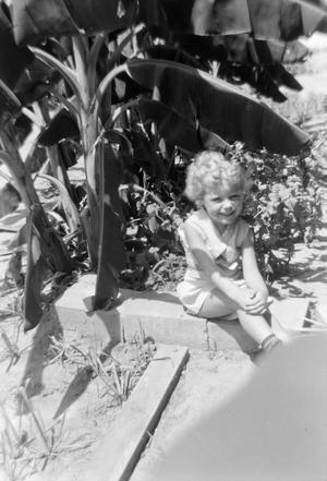 [Photograph of Carol Williams sitting by a flower bed]