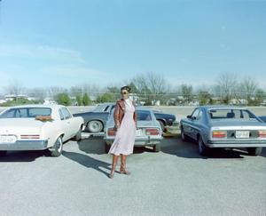 [Debby Herman posing in front of cars]