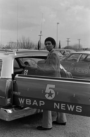 [Willie Monroe standing behind a WBAP automobile]