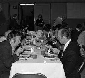 [Photograph of a group of individuals dining at an event]