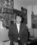 Photograph: [Ron Spain in front of football posters, 2]