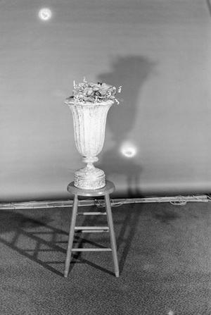 [Photograph of a vase on a stool]
