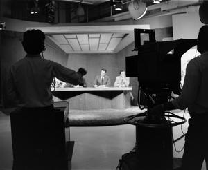 [Photo of newsmen and floor crew silhouette]