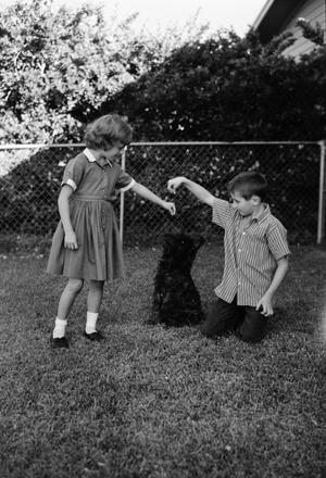 [Pam and Byrd Williams IV playing with dog, Angus, in a yard]