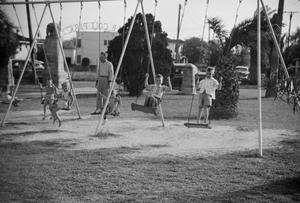 [Photograph of children playing on a swing set]