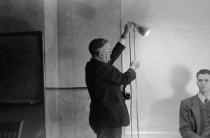 [Photograph of a photographer adjusting a lamp]