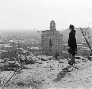 [Photograph of a woman standing on a ledge]