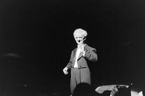 [Photograph of a man on stage in a tuxedo]