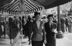 [Photograph of two women on a crowded sidewalk]