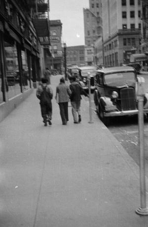 [Photograph of individuals walking down a sidewalk]