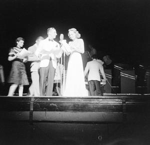 [Photograph of a group individuals gathered behind a microphone on stage, 2]
