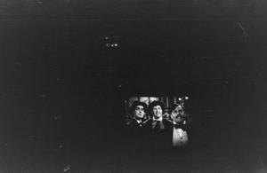 [Photograph of three people on a screen, 2]