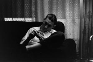 [Photograph of a man sitting on a couch with a camera]