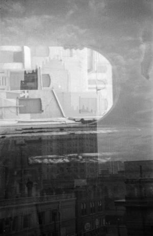 [Photograph of tall buildings in a city, double exposure]