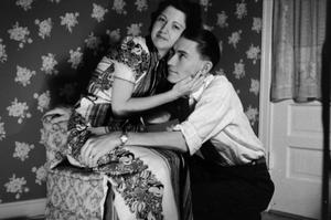 [Photograph of a couple posing in front of a floral-print background, 3]
