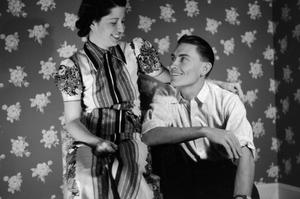 [Photograph of a couple posing in front of a floral-print background]
