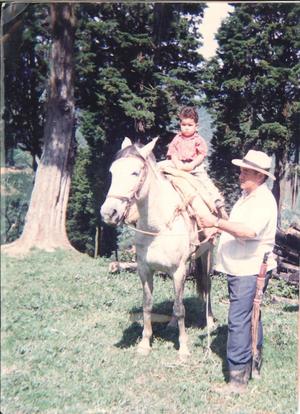 [Man helps young boy who is riding a horse]
