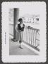 Photograph: [Photograph of Carol Williams posing on a front porch]