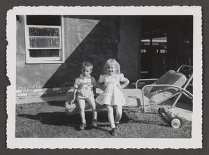 [Photograph of a little boy and girl sitting on a lawn chair]
