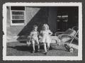 Photograph: [Photograph of a little boy and girl sitting on a lawn chair]