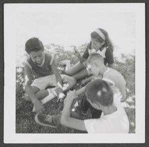 [Photograph of children sitting in the grass]
