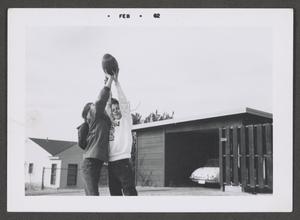 [Photograph of two children reaching for a football]