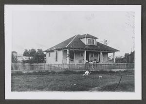 [Photograph of individuals sitting on the porch of a house]