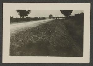 [Photo of men working on a dirt road]