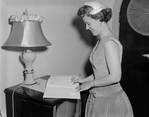 [A woman signing a guestbook]