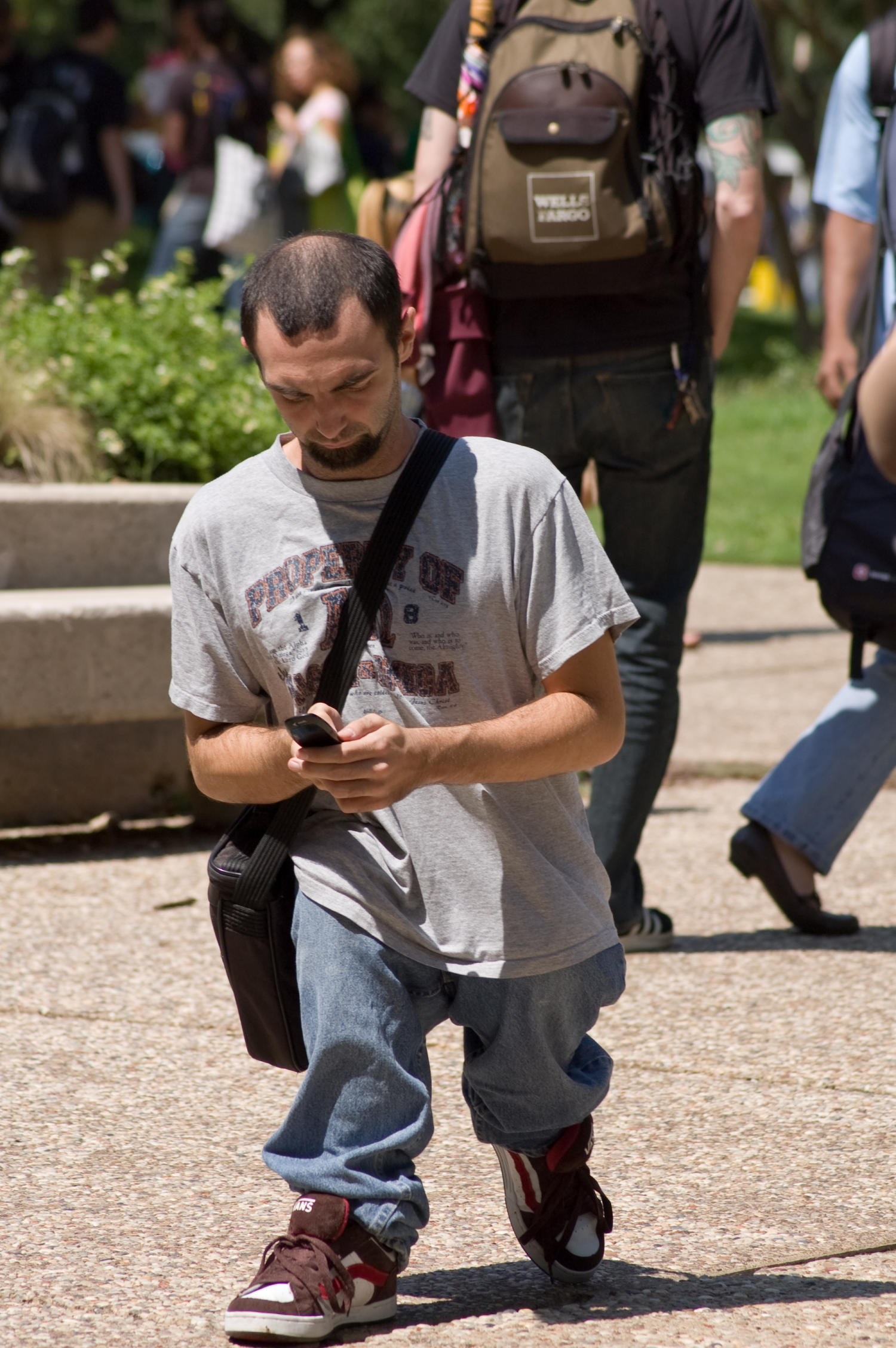 [UNT student walking and texting on campus] UNT Digital Library