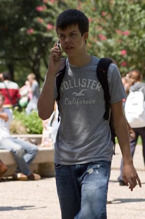 [Student walking with cell phone by ear]