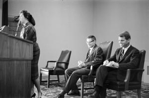 [Woman at podium with Robert F. Kennedy behind her]