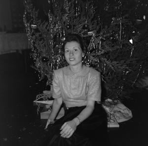 [Photograph of a woman sitting in front of a Christmas tree]