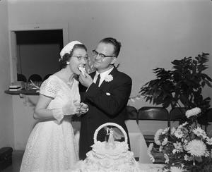 [Photograph of a groom feeding cake to his bride]