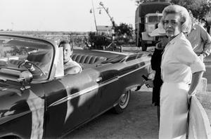 [Alice Faye and a man in a convertible]