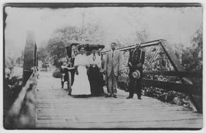 [Two women and two men standing on a bridge]